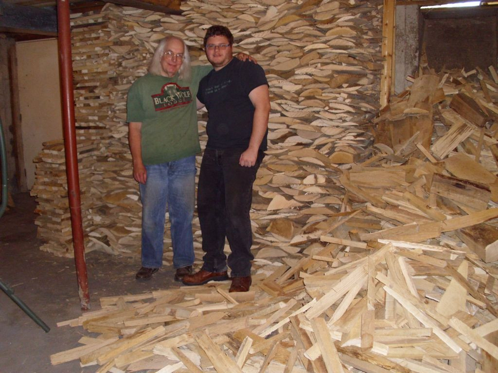 John and Braden standing next to a huge pile of wood.